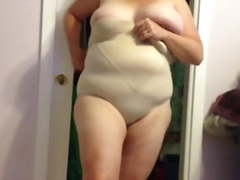 Wife putting on her girdle over her big tits